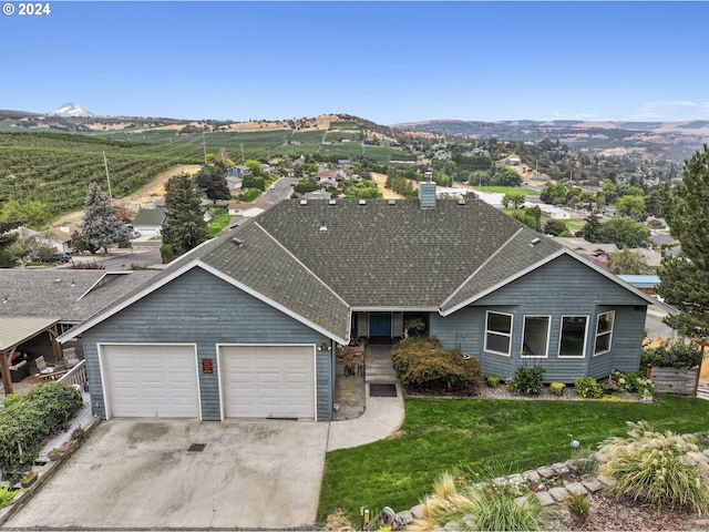 exterior space featuring a mountain view, a front lawn, and a garage