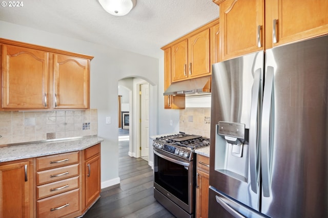 kitchen with light stone countertops, stainless steel appliances, dark hardwood / wood-style flooring, backsplash, and a textured ceiling