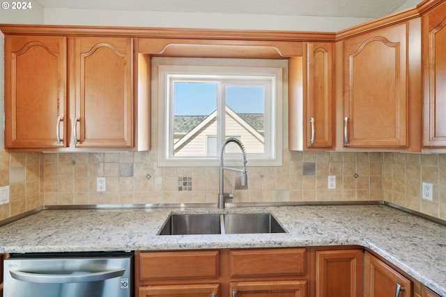 kitchen with stainless steel dishwasher, backsplash, light stone counters, and sink