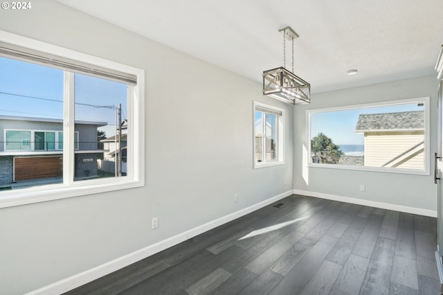 unfurnished dining area with a chandelier and dark hardwood / wood-style floors