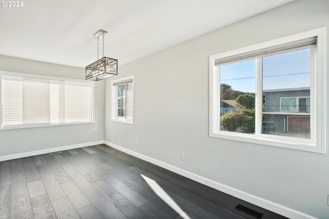 unfurnished dining area with a notable chandelier and dark hardwood / wood-style floors