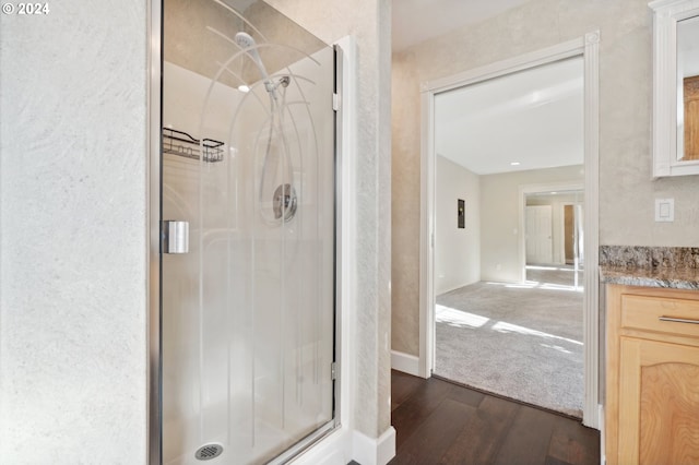 bathroom with wood-type flooring, vanity, and a shower with shower door