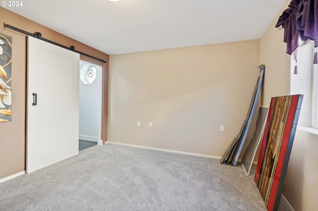 unfurnished bedroom featuring carpet and a barn door