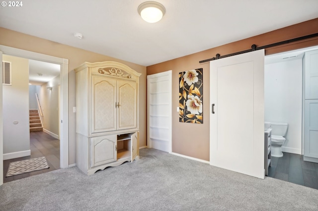 bedroom featuring a barn door, carpet floors, and connected bathroom