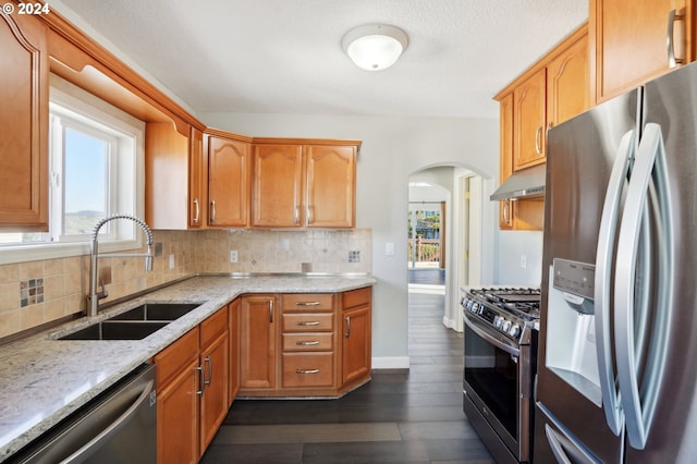 kitchen with light stone counters, sink, stainless steel appliances, and a wealth of natural light