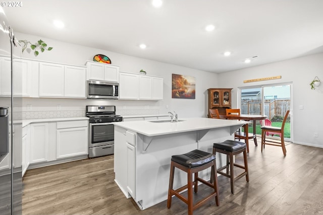 kitchen with stainless steel appliances, a center island with sink, sink, and white cabinets