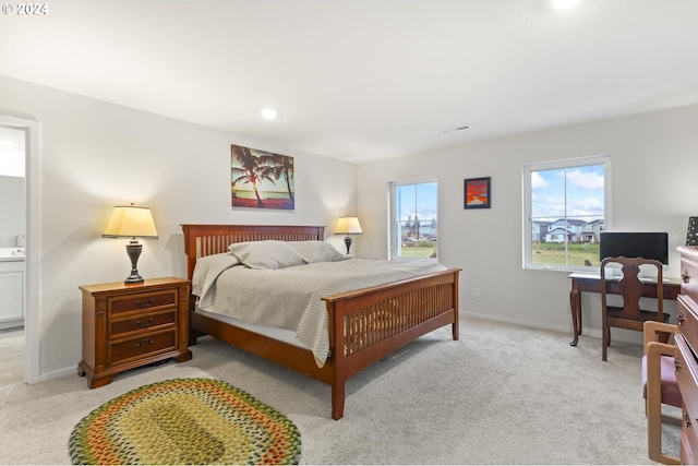 bedroom featuring ensuite bathroom and light colored carpet