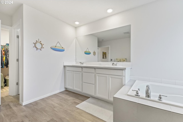 bathroom with a tub to relax in, vanity, and hardwood / wood-style flooring