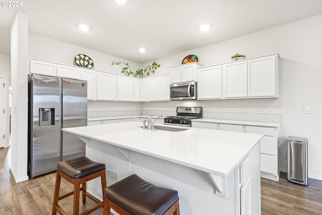 kitchen featuring a kitchen island with sink, appliances with stainless steel finishes, dark hardwood / wood-style floors, and a breakfast bar area