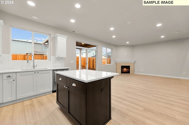 kitchen featuring decorative backsplash, white cabinetry, sink, and light hardwood / wood-style flooring