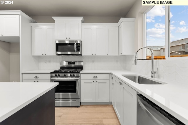 kitchen with backsplash, white cabinetry, sink, and appliances with stainless steel finishes