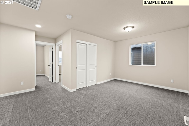 unfurnished bedroom with dark colored carpet, a textured ceiling, and a closet