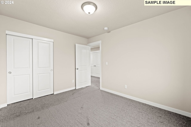 unfurnished bedroom featuring carpet flooring, a textured ceiling, and a closet