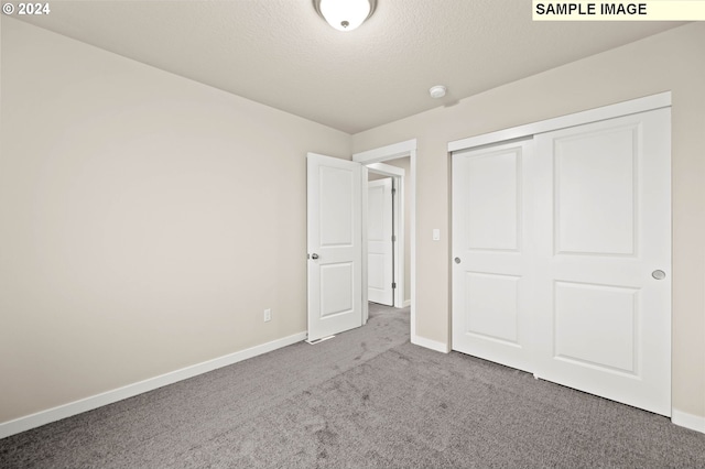 unfurnished bedroom with a closet, carpet, and a textured ceiling