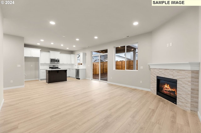 unfurnished living room featuring sink, a fireplace, and light wood-type flooring