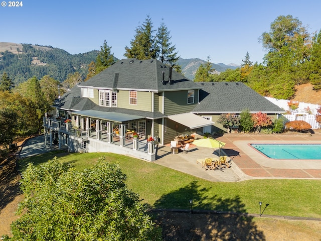 rear view of property featuring a patio area, a yard, and a mountain view