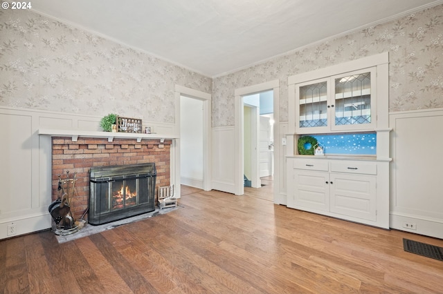 unfurnished living room featuring a fireplace, crown molding, and light hardwood / wood-style floors