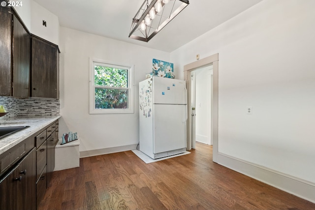 kitchen with light wood-type flooring, dark brown cabinetry, and white fridge