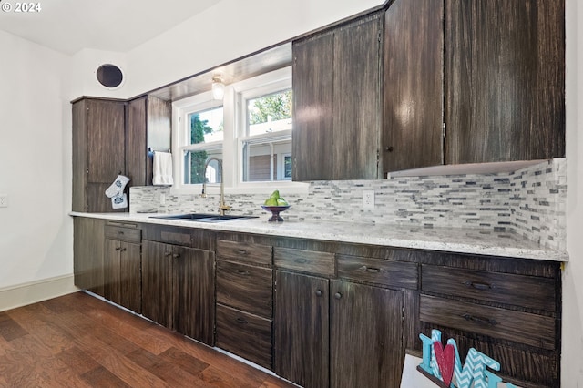 kitchen featuring dark brown cabinets, backsplash, dark wood-type flooring, and sink