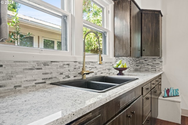 kitchen with dark brown cabinetry, light stone counters, and tasteful backsplash