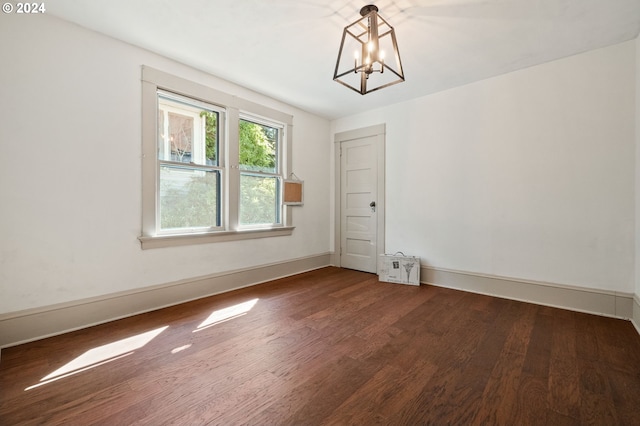 unfurnished room with an inviting chandelier and dark hardwood / wood-style floors