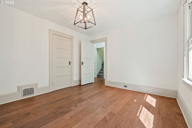 spare room featuring a notable chandelier and hardwood / wood-style floors