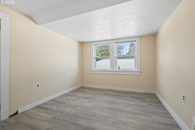 spare room with light wood-type flooring and a textured ceiling