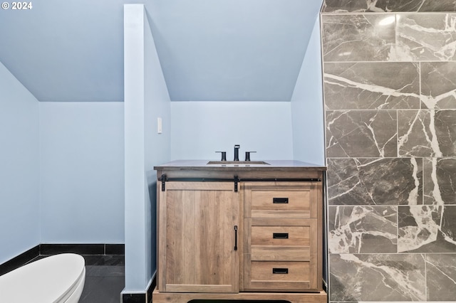 bathroom with vanity, lofted ceiling, toilet, and tile walls