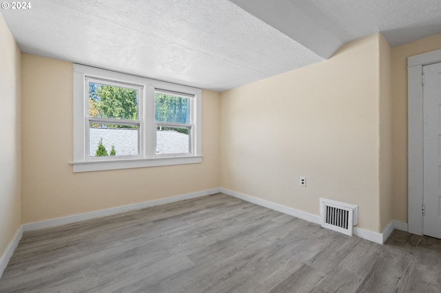 empty room featuring light hardwood / wood-style floors and a textured ceiling