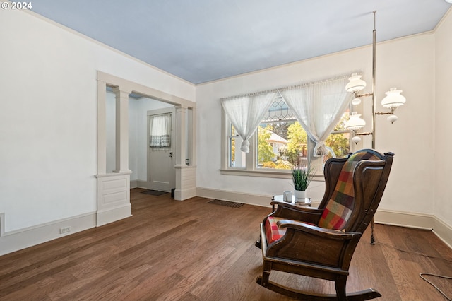 living area with an inviting chandelier, hardwood / wood-style flooring, and decorative columns