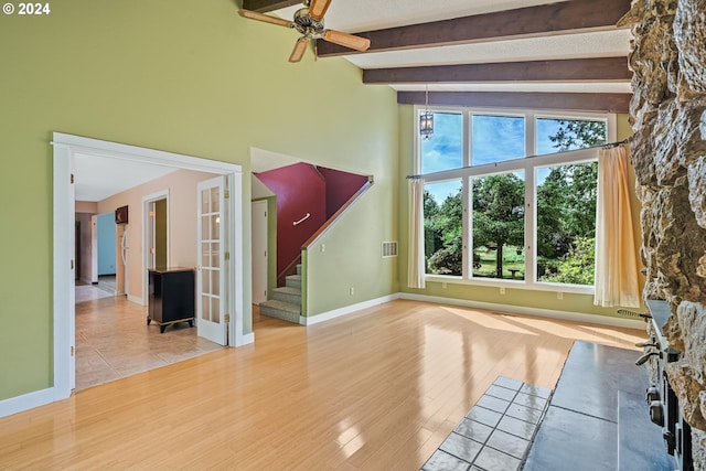 unfurnished living room featuring ceiling fan, lofted ceiling with beams, and light hardwood / wood-style floors