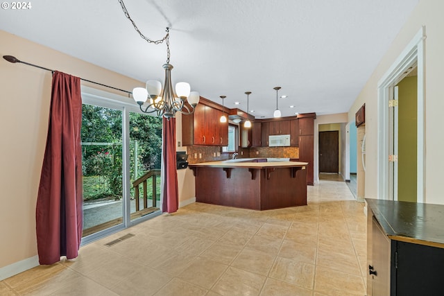 kitchen featuring tasteful backsplash, kitchen peninsula, light tile patterned floors, and a breakfast bar