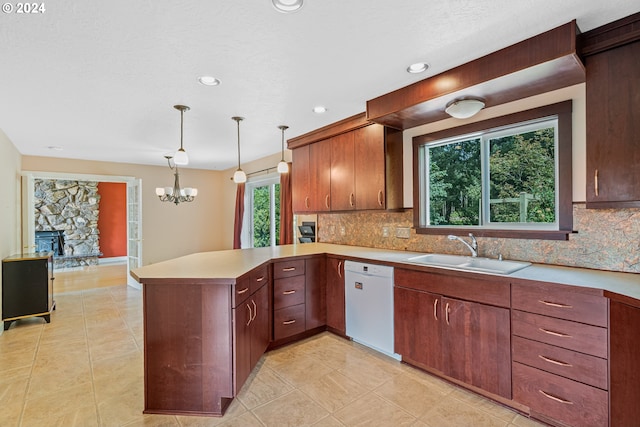 kitchen featuring a fireplace, white dishwasher, kitchen peninsula, sink, and decorative backsplash