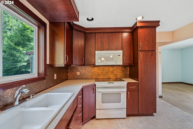 kitchen with light wood-type flooring, white appliances, backsplash, and sink