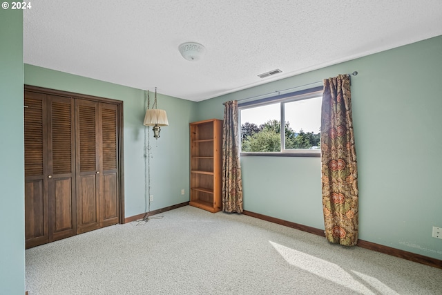 unfurnished bedroom featuring a textured ceiling, light colored carpet, and a closet