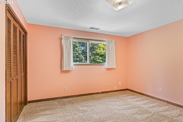 unfurnished bedroom with a textured ceiling, carpet, and a closet