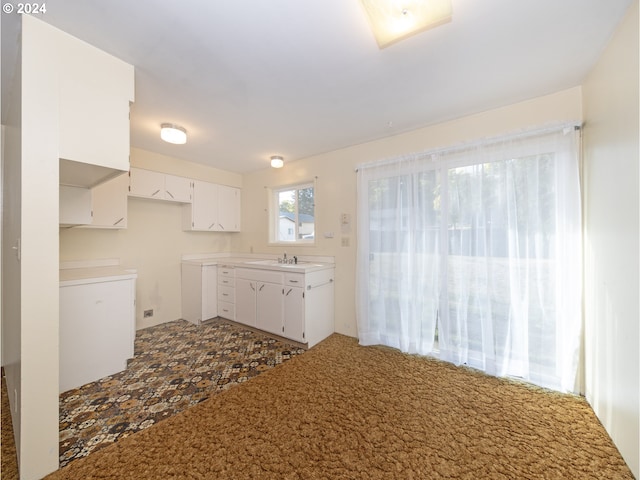 kitchen featuring white cabinets, carpet flooring, and sink