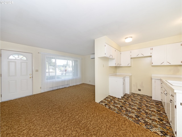 kitchen with a wall mounted air conditioner, sink, and white cabinets