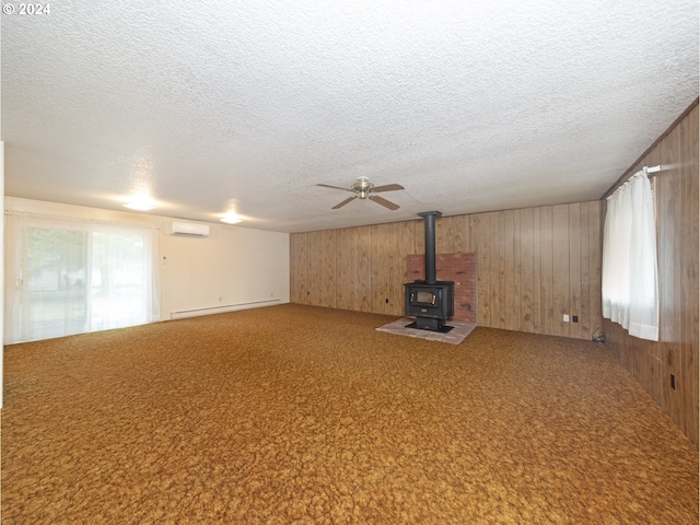 unfurnished living room with wood walls, ceiling fan, baseboard heating, a wall mounted air conditioner, and a textured ceiling