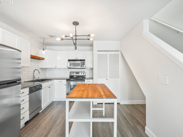 kitchen featuring decorative backsplash, appliances with stainless steel finishes, pendant lighting, an inviting chandelier, and white cabinetry