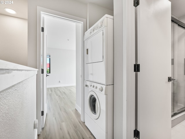 laundry area featuring light wood-type flooring and stacked washing maching and dryer