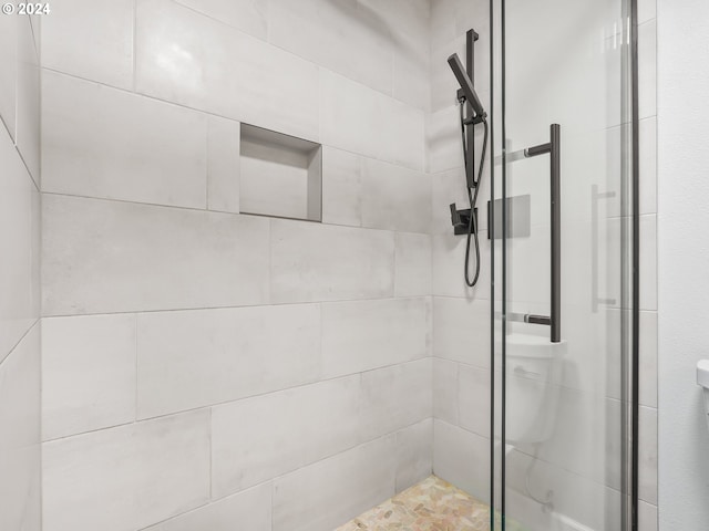 bathroom with a tile shower and toilet