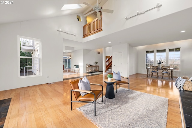 living room with light hardwood / wood-style floors, high vaulted ceiling, and a skylight