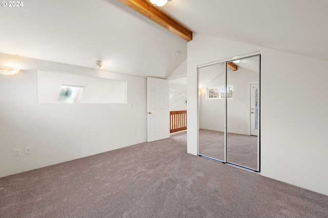 unfurnished bedroom featuring vaulted ceiling with beams, carpet floors, and a closet