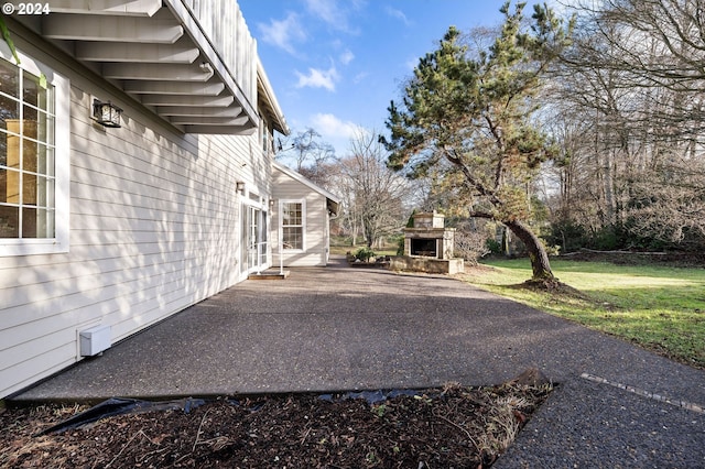 view of home's exterior featuring a patio, exterior fireplace, and a lawn