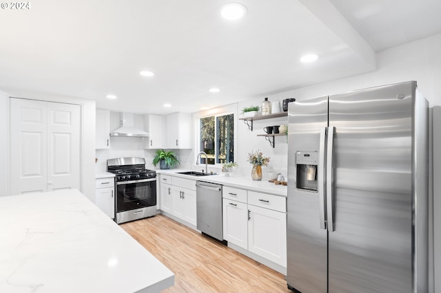 kitchen featuring sink, wall chimney exhaust hood, stainless steel appliances, light hardwood / wood-style flooring, and white cabinets