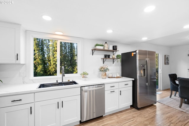 kitchen with white cabinetry, sink, appliances with stainless steel finishes, and light hardwood / wood-style flooring