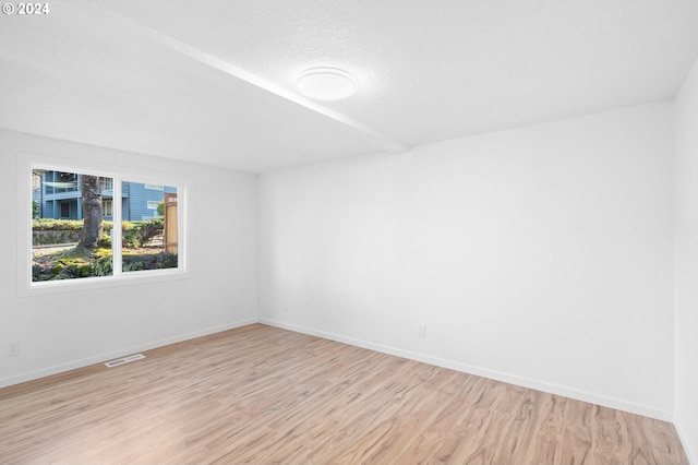 empty room with a textured ceiling and light hardwood / wood-style floors