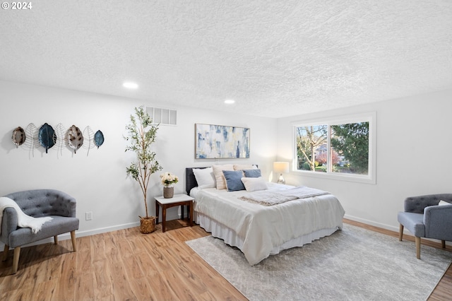 bedroom with light wood-type flooring and a textured ceiling