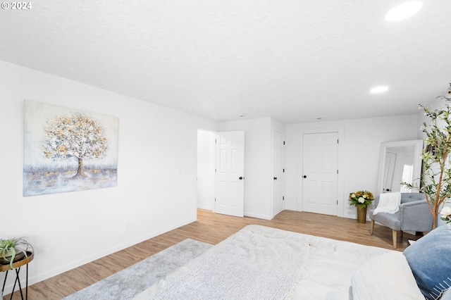 bedroom with light wood-type flooring and a textured ceiling